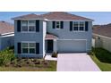 Charming two-story home with gray siding, dark shutters, well-maintained landscaping, and an attached two-car garage at 5470 Flint Hills Dr, Wimauma, FL 33598