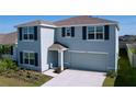 Two-story home boasts gray siding, dark shutters, well-maintained landscaping, and an attached two-car garage at 5470 Flint Hills Dr, Wimauma, FL 33598
