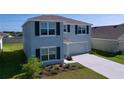 Two-story home boasts gray siding, dark shutters, well-maintained landscaping, and an attached two-car garage at 5470 Flint Hills Dr, Wimauma, FL 33598