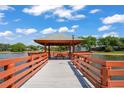 Wooden gazebo with seating area on a pier overlooking a serene lake at 8405 Divot Way, Port Richey, FL 34668