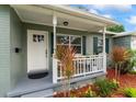 Inviting covered front porch with decorative landscaping, a white railing, and seating space perfect for relaxing at 9000 Bay Ne St, St Petersburg, FL 33702