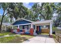 Quaint blue home featuring a welcoming front porch, complemented by a practical covered parking space at 1019 E Mohawk Ave, Tampa, FL 33604