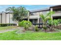 Condo exterior featuring lush tropical landscaping, a well-maintained lawn, and exterior stairs leading to a second-story entrance at 10265 Gandy N Blvd # 1702, St Petersburg, FL 33702