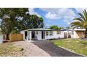 This home features a newly paved driveway and a covered front porch with chairs at 10408 118Th Ave, Largo, FL 33773