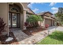 Inviting front entrance featuring a brick walkway, manicured landscaping, and a three-car garage at 1342 Salmonberry St, Wesley Chapel, FL 33543