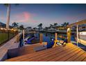 Inviting waterfront space featuring comfortable seating, wooden dock, boat lift, and scenic views of the waterway at dusk at 1424 47Th Ne Ave, St Petersburg, FL 33703