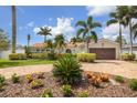 Charming home featuring a paver driveway, lush landscaping, mature palm trees, and a well-manicured lawn under a bright blue sky at 1424 47Th Ne Ave, St Petersburg, FL 33703