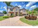 Beautiful two-story home featuring a manicured lawn, mature palm trees, and a brick paver driveway at 2566 Lake Manor Dr, Land O Lakes, FL 34639