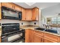 A kitchen with wooden cabinets, granite countertops, and black appliances at 2621 Cove Cay Dr # 302, Clearwater, FL 33760