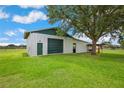 Large metal barn with a roll-up door, side entry, and lush green grass at 39905 Townsend Rd, Dade City, FL 33525