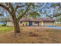 Single-story home featuring a blue front door, well-kept lawn, and large shade tree at 5749 Southernview Dr, Zephyrhills, FL 33541