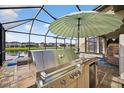 Entertain with ease using the outdoor kitchen and stainless steel grill by the screened-in pool at 7570 Sweeter Tide Trl, Wesley Chapel, FL 33545