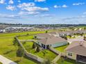 An aerial view of a community home with fenced backyard, lake, and view of the neighborhood at 8174 Wheat Stone Dr, Zephyrhills, FL 33540