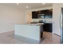 Well-lit kitchen featuring dark cabinets, stainless steel appliances, and an island with sleek countertops at 8210 Juning Cv, Wesley Chapel, FL 33545