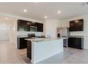 Modern kitchen with stainless steel appliances, dark cabinetry, and a large center island with granite countertops at 8210 Juning Cv, Wesley Chapel, FL 33545