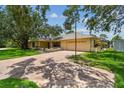 Angle view of a single story residence showing mature shade trees, a two car garage, basketball hoop, and manicured lawn at 1443 54Th Ne Ave, St Petersburg, FL 33703