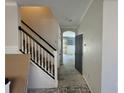 Hallway leading to the kitchen with white walls, staircase, and an open doorway at 1015 Windton Oak Dr, Ruskin, FL 33570