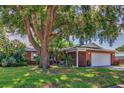 Charming brick home featuring a lush front yard, mature trees, and an attached two-car garage at 13029 111Th Ln, Largo, FL 33778