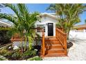 Inviting entrance with a newly stained wood deck, lush landscaping, and a modern black front door at 13148 3Rd E St, Madeira Beach, FL 33708