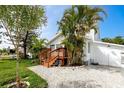 A charming side view of the house showcasing tropical foliage, white gravel, and a newly stained wood deck at 13148 3Rd E St, Madeira Beach, FL 33708