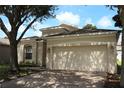Beige single-story home featuring mature landscaping and a two-car garage at 221 Fairmont Dr, Spring Hill, FL 34609