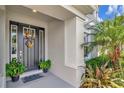 Cozy front porch showcasing a black front door with decorative sunflower wreaths and potted plants at 26972 Evergreen Chase Dr, Wesley Chapel, FL 33544