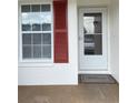 Close-up of a front entry door with red shutters and a welcome mat for a warm invitation at 3007 Wainwright Ct, New Port Richey, FL 34655