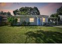 Charming single-story home at dusk featuring a bright blue door, covered parking, and a well-manicured lawn at 4009 S Renellie Dr, Tampa, FL 33611