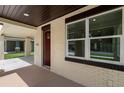 Covered porch entry featuring brick detail around the windows, a dark red front door, and concrete flooring at 5701 N 20Th St, Tampa, FL 33610