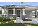 Close up of the home's gray exterior, decorative glass front door, and landscaped entryway at 5705 N 20Th St, Tampa, FL 33610