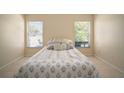 Bright bedroom featuring tile flooring, a bed with decorative pillows, and natural light through two windows at 7534 Oxford Garden Cir, Apollo Beach, FL 33572