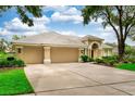Exterior view of home with a well-manicured lawn, mature trees, and a spacious three-car driveway at 9116 Woodridge Run Dr, Tampa, FL 33647