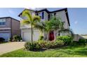 Charming two-story home featuring mature landscaping, a red front door, and a spacious two-car garage at 9334 Lemon Drop Loop, Sun City Center, FL 33573