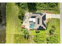 Aerial view of a property with a pool, solar panels, and lush green surroundings, offering privacy at 1857 N San Mateo Dr, North Port, FL 34288