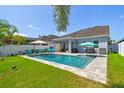 Backyard oasis featuring a refreshing pool, patio, lounge seating, and lush green lawn at 11307 Quiet Forest Dr, Tampa, FL 33635