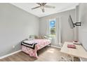 Cozy bedroom with light gray walls, wood-look flooring, and a window providing natural light at 11423 Brighton Knoll Loop, Riverview, FL 33579
