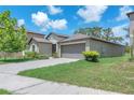 A tan single-story home featuring an attached two car garage and a well maintained green lawn at 12907 Wildflower Meadow Dr, Riverview, FL 33579