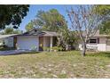 A ranch-style home features a large tree, an attached two-car garage and drought-tolerant landscaping at 201 Westwood N Ter, St Petersburg, FL 33710