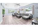 Bright living room features tile flooring, large windows, a ceiling fan, and a modern leather sectional at 2861 Pinellas Point S Dr, St Petersburg, FL 33712