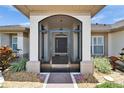 Inviting front entrance with screen door, featuring neutral tones and charming landscaping at 304 Caloosa Palms Ct, Sun City Center, FL 33573