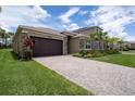 Charming home featuring lush landscaping, a stone facade, and a paver driveway under a sunny sky at 3318 Woodland Brook Way, Wesley Chapel, FL 33543