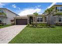 Charming single-Gathering home featuring lush landscaping, a stone facade, and a paver driveway under a sunny sky at 3318 Woodland Brook Way, Wesley Chapel, FL 33543