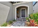 Welcoming entrance featuring a gray front door, potted plants, bench and brick paver pathway at 37820 Beacon Brick Dr, Zephyrhills, FL 33540
