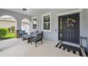 Covered front porch area features an outdoor seating area and a decorative floral wreath at 4151 Little Gap Loop, Ellenton, FL 34222