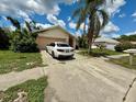 View of one-story home and driveway with white car in front of attached garage, against a cloudy sky at 8635 Braxton Dr, Hudson, FL 34667