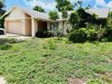 Exterior of single-story home needing landscaping with an attached garage on a partially cloudy day at 8635 Braxton Dr, Hudson, FL 34667
