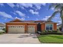 Charming single-story home with a three-car garage, well-maintained landscaping, and an orange painted stucco facade at 11614 Ashton Field Ave, Riverview, FL 33579