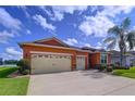 Charming single-story home with a three-car garage, well-maintained landscaping, and an orange painted stucco facade at 11614 Ashton Field Ave, Riverview, FL 33579