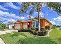 Charming single-story home with a three-car garage, well-maintained landscaping, and an orange painted stucco facade at 11614 Ashton Field Ave, Riverview, FL 33579