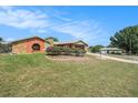 Expansive front yard with meticulously manicured lawn, mature landscaping, and a charming brick pathway leading to the house at 159 Canby Cir, Spring Hill, FL 34606